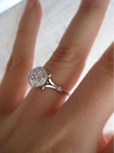 a close up of a person's hand with a diamond ring on their finger