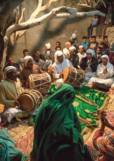 a group of people sitting around each other on top of a floor covered in rugs