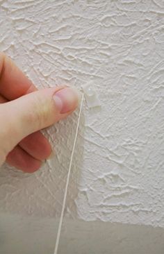 someone is painting the wall with white paint on it and pulling thread from the corner