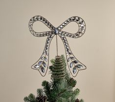 a christmas ornament hanging from the side of a pine tree with a bow on it