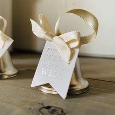 two bells with ribbons tied around them on a table