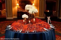 two vases filled with white flowers sitting on top of a blue table cloth covered table