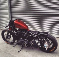 a red and black motorcycle parked in front of a garage door