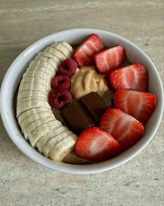 a white bowl filled with sliced bananas, strawberries and chocolate