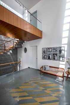 a living room with stairs and pictures on the wall next to a wooden bench in front of a stair case