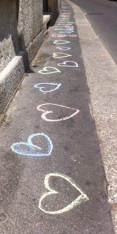 a sidewalk with chalk writing on it next to a building and street sign that says love