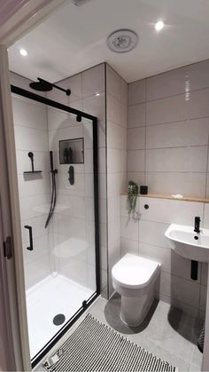 a bathroom with a toilet, sink and shower stall in the middle of it is shown