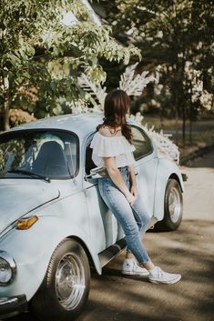 a woman sitting on the hood of a car