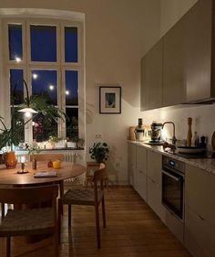 a kitchen with a table and chairs in front of a large window at night time