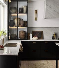 a kitchen with marble counter tops and black cabinets