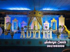 a stage set up for an event with blue and yellow decorations on the sides, gold curtains, and white drapes