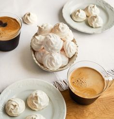 three plates with pastries and two cups of coffee on a wooden table next to each other