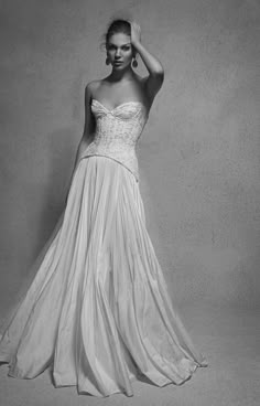 a woman in a long white dress posing for the camera with her hand on her head