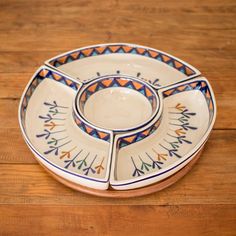 three plates with colorful designs on them sitting on a wooden table