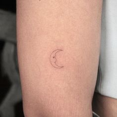 a woman's arm with a small crescent tattoo on the left side of her thigh