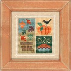 a cross stitch picture frame with an image of pumpkins and other things on it