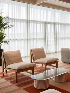 a living room with couches, chairs and a coffee table in front of a large window