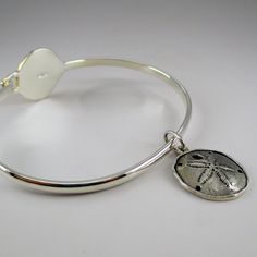 "This sterling silver Scallop Shell Bangle features a silver band with a ridged, gold vermeil scallop shell. The bangle accommodates large spacer beads and traditional charms. Marked Brown County Silver and Sterling inside the band. Also marked S.W.P. for designer Steven Wesley Patterson. Brand new, never worn condition. Available in medium only. Medium - 7.25\" Approximate weight is 14 grams *Sand dollar charm sold separately." Adjustable Silver Shell-shaped Jewelry, Adjustable Silver Jewelry With Starfish Charm, Silver Shell Jewelry With Lobster Clasp, Silver Shell-shaped Jewelry With Lobster Clasp, Adjustable Silver Bracelet With Ocean-inspired Style, Adjustable Silver Bracelets With Ocean-inspired Style, Adjustable Silver Charm Bracelet With Starfish, Adjustable Silver Ocean-inspired Bracelets, Silver Adjustable Ocean-inspired Bracelets