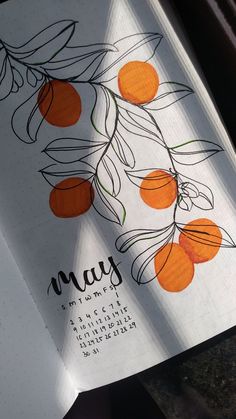 an open notebook with oranges on it and the word may written in cursive writing