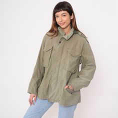 Vintage 90s military jacket in faded olive green with a zip off hood and cargo pockets. Faded and distressed. Please see measurements and condition below. Every garment we sell is authentic vintage! You will receive the exact item photographed. Condition: Distressed. has wear and fading throughout, See photos Best fits women's: Large Best fits men's: Labelled Medium short Material:  Cotton MEASUREMENTS Taken from seam to seam while the garment is lying flat. Double the armpit, waist, and hips For reference, model is 5'9" and measures 35-27.5-39. Length from Top: 27" Armpit to Armpit: 24" Waist: 23" Shoulder to Shoulder: 20" Sleeve: 22" For sales and promotions, follow us @Shopexile Vintage Parka With Flap Pockets For Outdoor, Vintage Outdoor Parka With Flap Pockets, Spring Military Style Khaki Parka, Fall Combat Hooded Utility Jacket, Vintage Parka For Fall Outdoor Activities, Vintage Parka For Outdoor Activities In Fall, Vintage Green Utility Jacket For Outdoor, Combat Style Khaki Parka For Fall, Olive Hooded Utility Parka