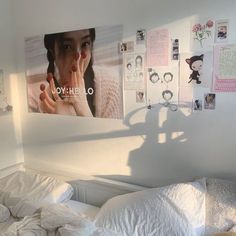 an unmade bed in a small room with posters on the wall