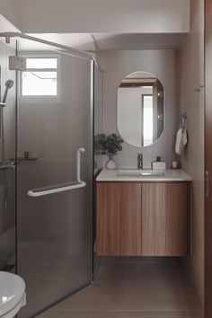 a bathroom with a sink, mirror and shower stall in the corner next to a toilet