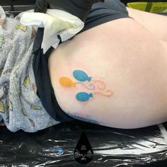 a woman laying on the ground with her stomach covered in blue and orange scissors tattoo