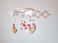 a crib mobile with chickens and roosters hanging from it's sides in the shape of clouds