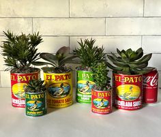 four cans with plants in them sitting on a table