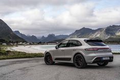 the rear end of a silver porsche cayenne parked in front of some mountains