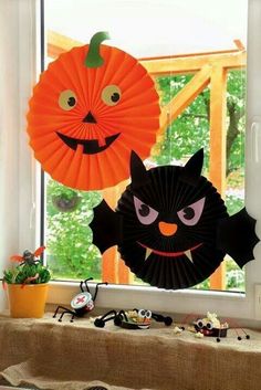 two halloween decorations on a window sill with pumpkins and bats hanging from the windowsill