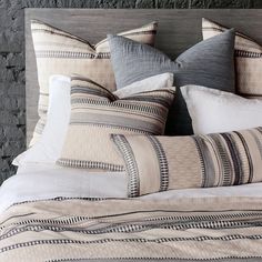 a bed with several pillows on top of it and a brick wall behind the headboard