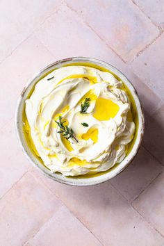 a bowl filled with whipped cream and topped with lemon zest on a pink tile floor