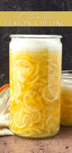 a mason jar filled with lemons on top of a wooden table next to two jars