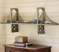 a wooden table topped with two metal shelves filled with toy cars next to a wall