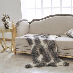 a couch with some pillows on it and a table in front of the couch is covered by a cowhide rug