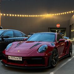 a red sports car parked in front of a building next to other cars on the street