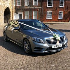 a silver car parked in front of a building with a white ribbon tied to it