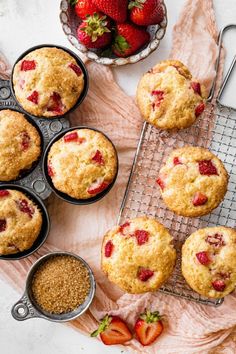 strawberry muffins cooling on a wire rack next to bowls of strawberries