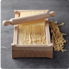 a wooden box filled with pasta next to a rolling pin