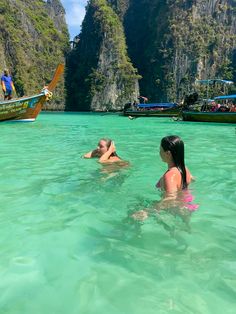 two people swimming in the ocean near boats