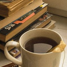 a cup of coffee sitting on top of a table next to stacks of books and magazines