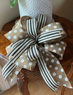 a polka dot bow sitting on top of a chair next to a potted plant