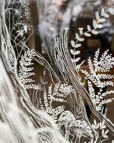 an etched glass window with white flowers and leaves