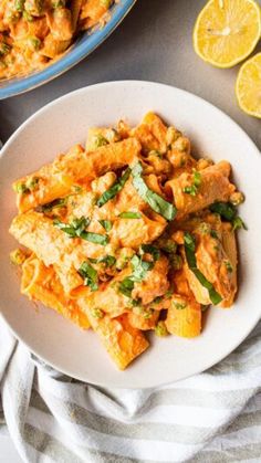 a white plate topped with pasta next to sliced lemons