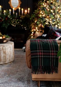 a living room decorated for christmas with lights on the trees in the background and plaid blanket