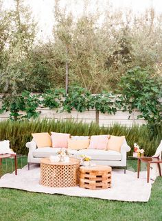 an outdoor seating area with couches, tables and chairs in front of some bushes