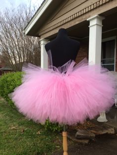 a mannequin wearing a pink tutu skirt in front of a house,