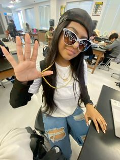 a woman wearing sunglasses and holding her hand up in front of the camera with both hands