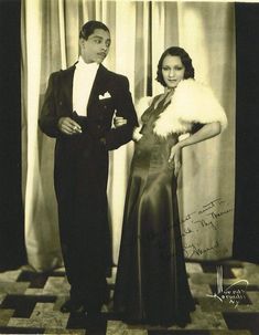 an old black and white photo of a man and woman in formal wear standing next to each other